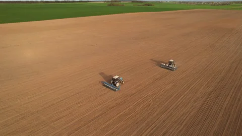 Tractor sowing seed on plowed field. Sowing seeds of corn and sunflower. 库存影片 193720954