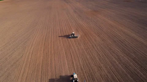 Tractor sowing seed on plowed field. Sowing seeds of corn and sunflower. 動画素材 193727950