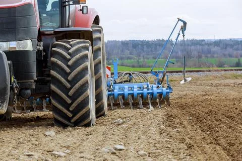 A tractor sows cereal crops with a precision seeder in the field. Stock Photos