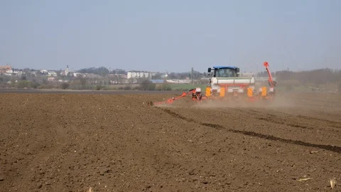 Tractor sows corn. Modern tractor sows the field with wheat seeds Stock Footage 128099488