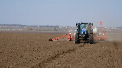 Tractor sows corn. Modern tractor sows the field with wheat seeds Stock Footage 128099533
