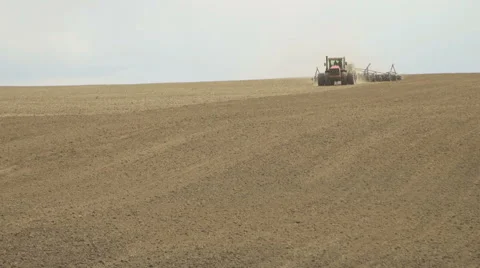 A tractor sows plowed field using a seeder Stock Footage 64619687