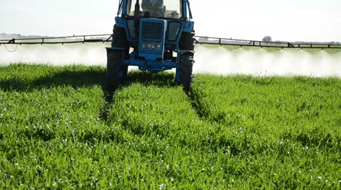 Tractor spray fertilize field with pesticide chemical in evening Stock Footage