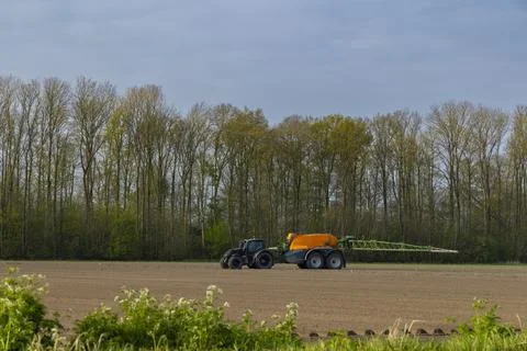 Tractor with sprayer during spring work on the field Stock Photos