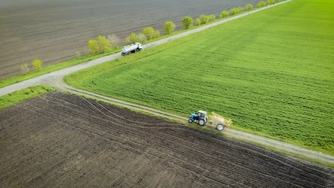 Tractor with sprayer pulls up to truck with tank of toxic chemicals for Stock Footage 107941891