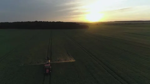 Tractor spraying endless green field on the sunset. Aerial drone shot Stock Footage 133998925