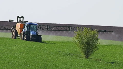 Tractor spraying field, rural landscape in countryside Stock Footage 63237093
