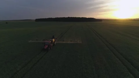 Tractor spraying green field on the sunset. Aerial drone shot Stock Footage 133998970