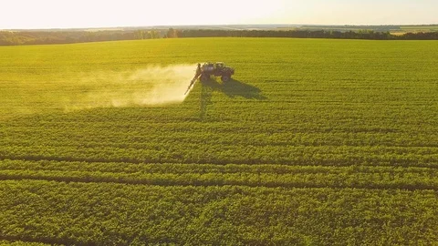 Tractor spraying pesticides on soybean field with sprayer at spring. Aerial Stock Footage