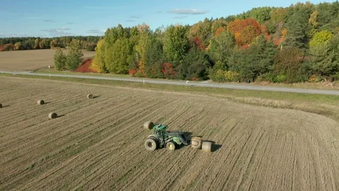 Tractor stacking and loading hay bales. Aerial slow flying backwards Vídeos de archivo 119063760
