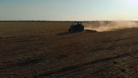 Tractor with tillage unit at end of working day in field at sunset Stock Footage 106227214