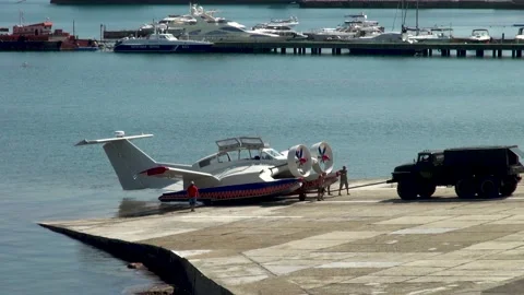 Tractor is towing multi-purpose ekranoplan Ivolga from sea towards parking lot. Stock Footage 135318928