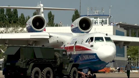 Tractor tows Be-200ES multi-purpose amphibian along airfield to parking lot. Stock Footage 132979860