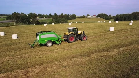 Tractor with trailed bale machine works on the field Agricultural work, baling Stock Footage 143078241