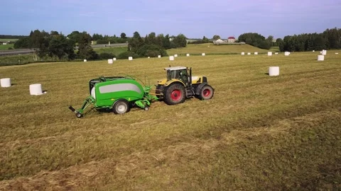 Tractor with trailed bale machine works on the field Agricultural work, baling Stock Footage 143082632