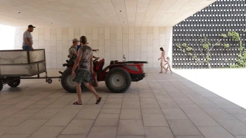 A tractor with a trailer carries workers in the park on a sunny day in front of  Stock Footage 120752908