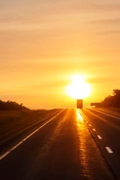 Tractor trailer driving on empty highway at dawn Stock Photos