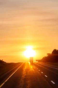 Tractor trailer driving on empty highway at dawn Stock Photos
