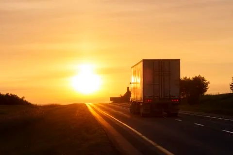 Tractor trailer driving on empty highway at dawn Stock Photos