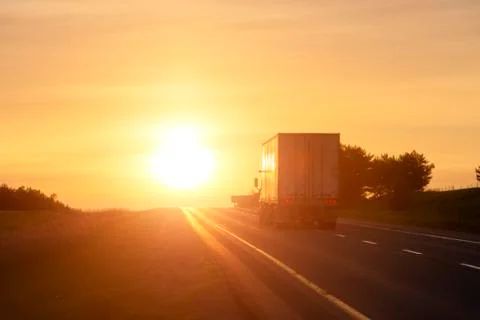 Tractor trailer driving on empty highway at dawn Stock Photos