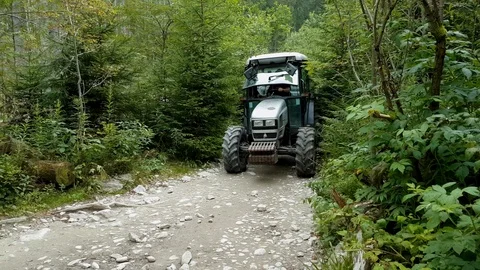 Tractor with trailer driving through a very narrow gravel track in the mountains Stock Footage 98207701