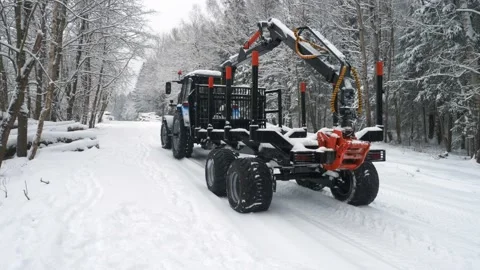A tractor with a trailer for loading logs backs up in the forest Stock Footage 169548736