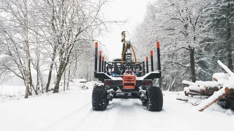 A tractor with a trailer moves empty on a snow-covered road in the forest Stock Footage 169548711