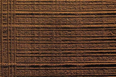 Tractor tread marks forming forming pattern in plowed field soil, aerial sh.. Stockfoto's