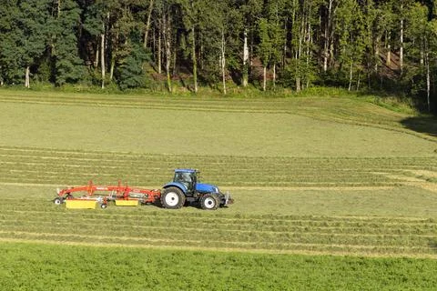 Tractor turning hay in spring meadow, Jura, France Stock Photos