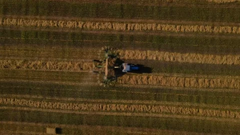 A tractor uses a trailed bale machine to collect straw in the field. Stock Footage 157276233