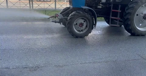 Tractor watering paths on the street Stock Footage 244938592