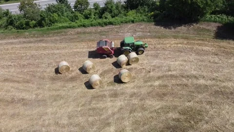Tractor at work producing round bales of hay Video stock 130983084