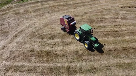 Tractor at work producing round bales of hay Vídeos de archivo 130983118