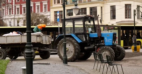 A tractor with a worker in the trailer stands in the middle of the city Stock Footage 240106373