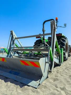 Tractor working on the beach to prepare sand for visitors during a sunny day Stock Photos
