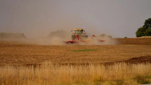Tractor working a distant field with dust rising, wide view Stock Footage 345530633