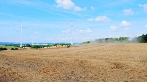 Tractor working in the field against the backdrop of rotating windmills Stock Footage 231288140