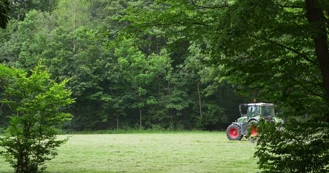 Tractor working on the field on a background of green forest Stock Footage 110945664