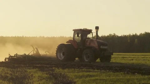 Tractor Working Field In Dust Cloud At Sunset Agricultural Machinery During.. Stock Footage 336943450
