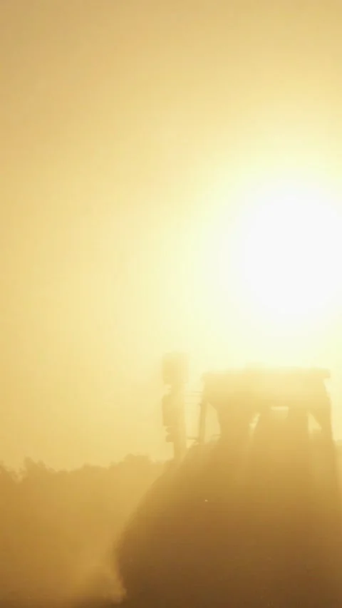 Tractor Working In Field At Sunset Through Dust And Sun Rays Atmospheric Ru.. Stock Footage 337444796