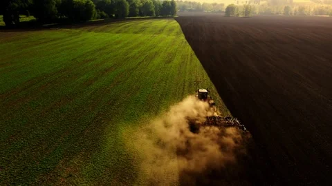 Tractor working the fields at sunrise in a rural landscape with dust clouds Video stock 284199217