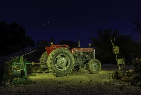Tractor working in the fields under the night sky Stock Photos