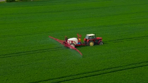 Tractor working on large wheat field. Agricultural vehicle operating across wide Stock Footage 328358692