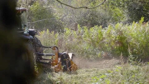 Tractor working with a mulcher, rotary tiller, shredding grass and brambles 库存影片 163213620