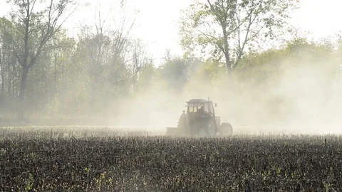 A tractor works the field with the light of the sunset Stock Footage 83894611