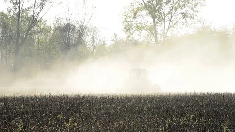 A tractor works the field with the light of the sunset Stock Footage 83894864
