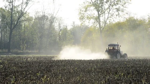 A tractor works the field with the light of the sunset Stock Footage 83894930