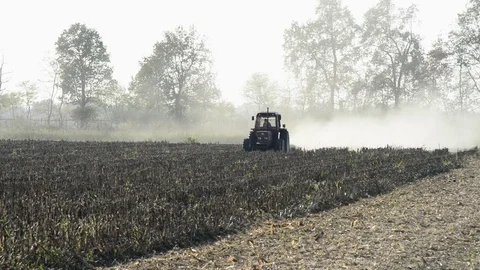 A tractor works the field with the light of the sunset Stock Footage 83895195
