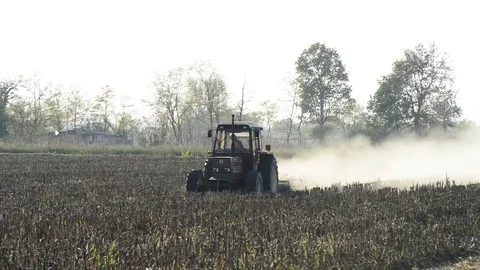 A tractor works the field with the light of the sunset Stock Footage 83895403