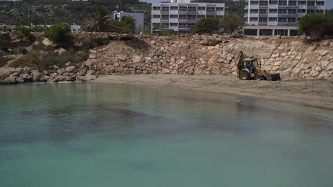Tractor works near the water. Improving of sandy beach of sea resort. Panning Stock Footage